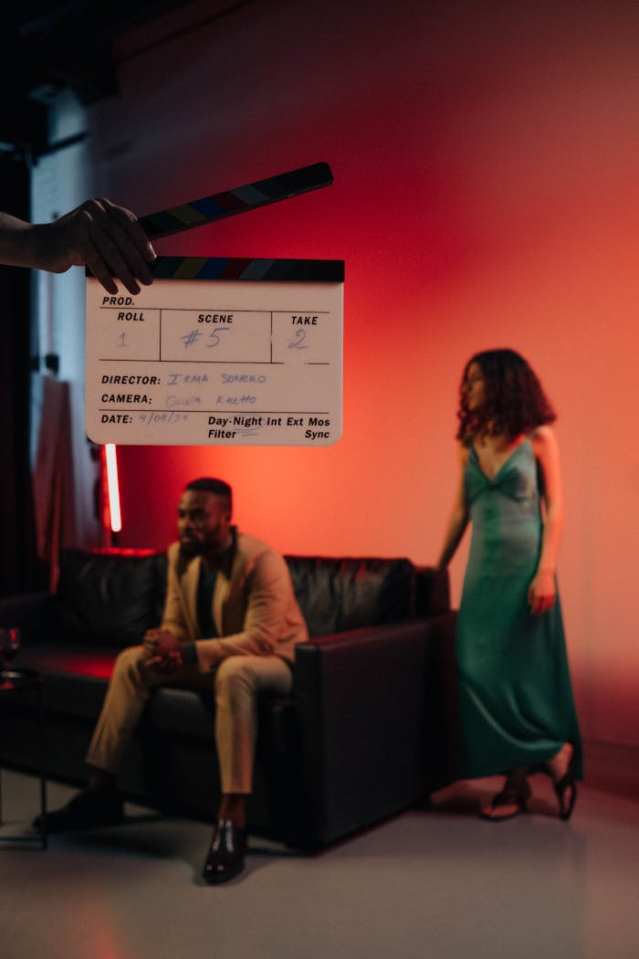 Actors on a film set with a clapperboard signaling action.