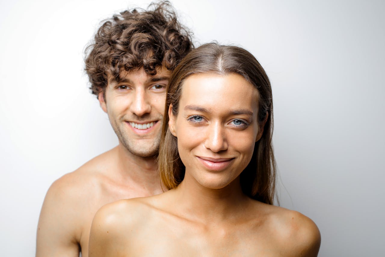 Happy couple smiling intimately against a white background, showcasing togetherness and joy.